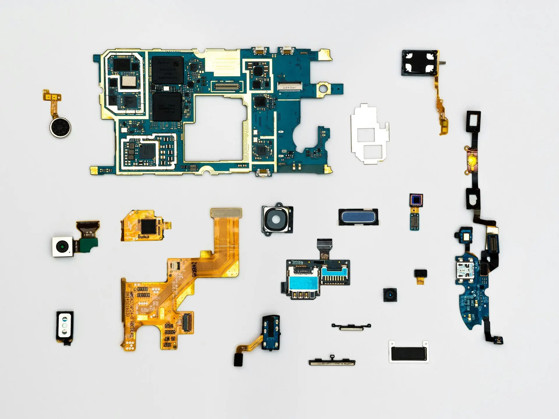 Auseinandergenommene Smartphone-Komponenten, darunter Platinen und Kameras, lagen verstreut auf einer hellgrauen Oberfläche.