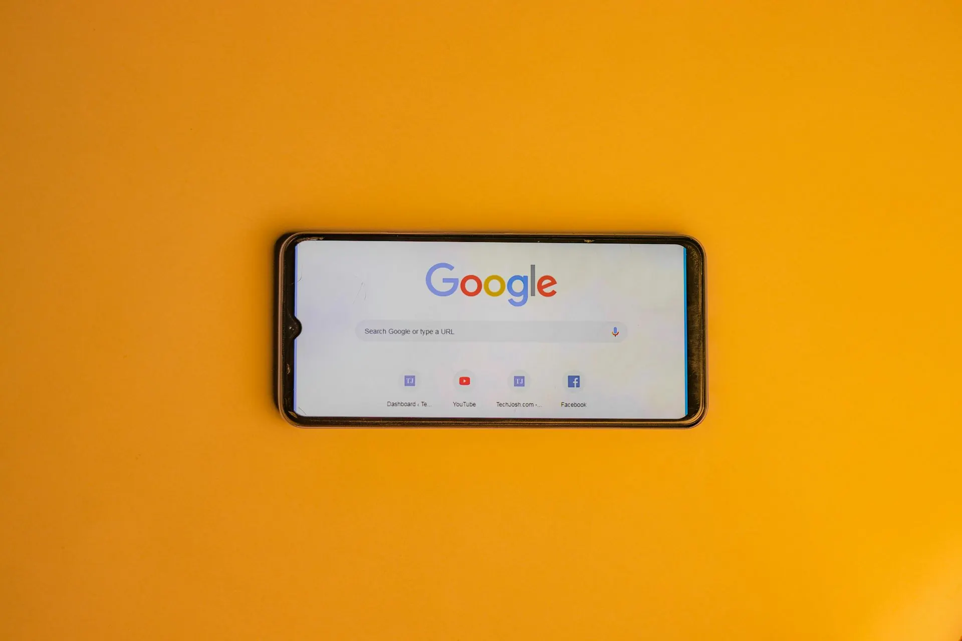 Smartphone mit der Google-Startseite auf hellgelbem Hintergrund