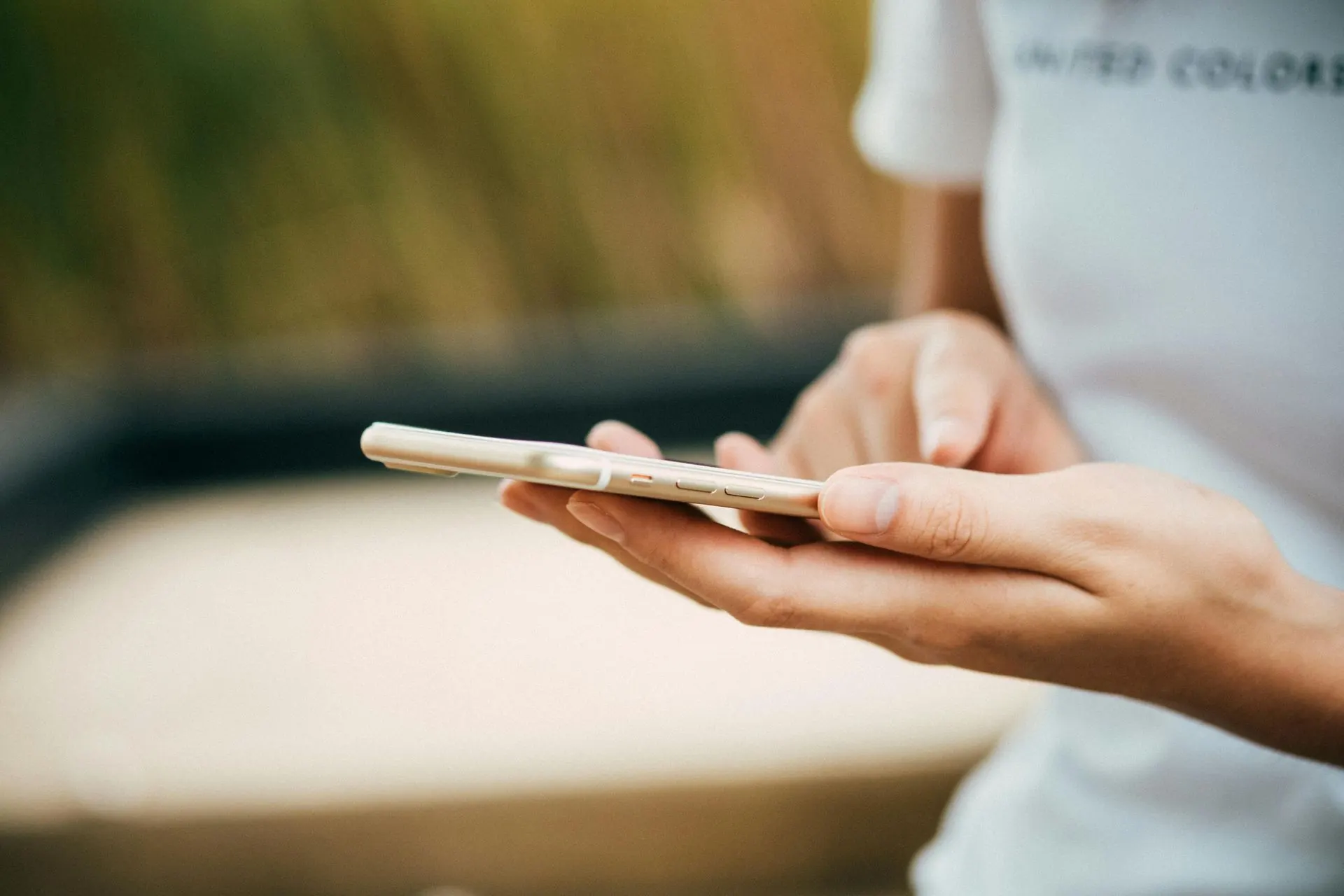 Person, die im Freien ein Smartphone mit zwei Fingern hält und benutzt.