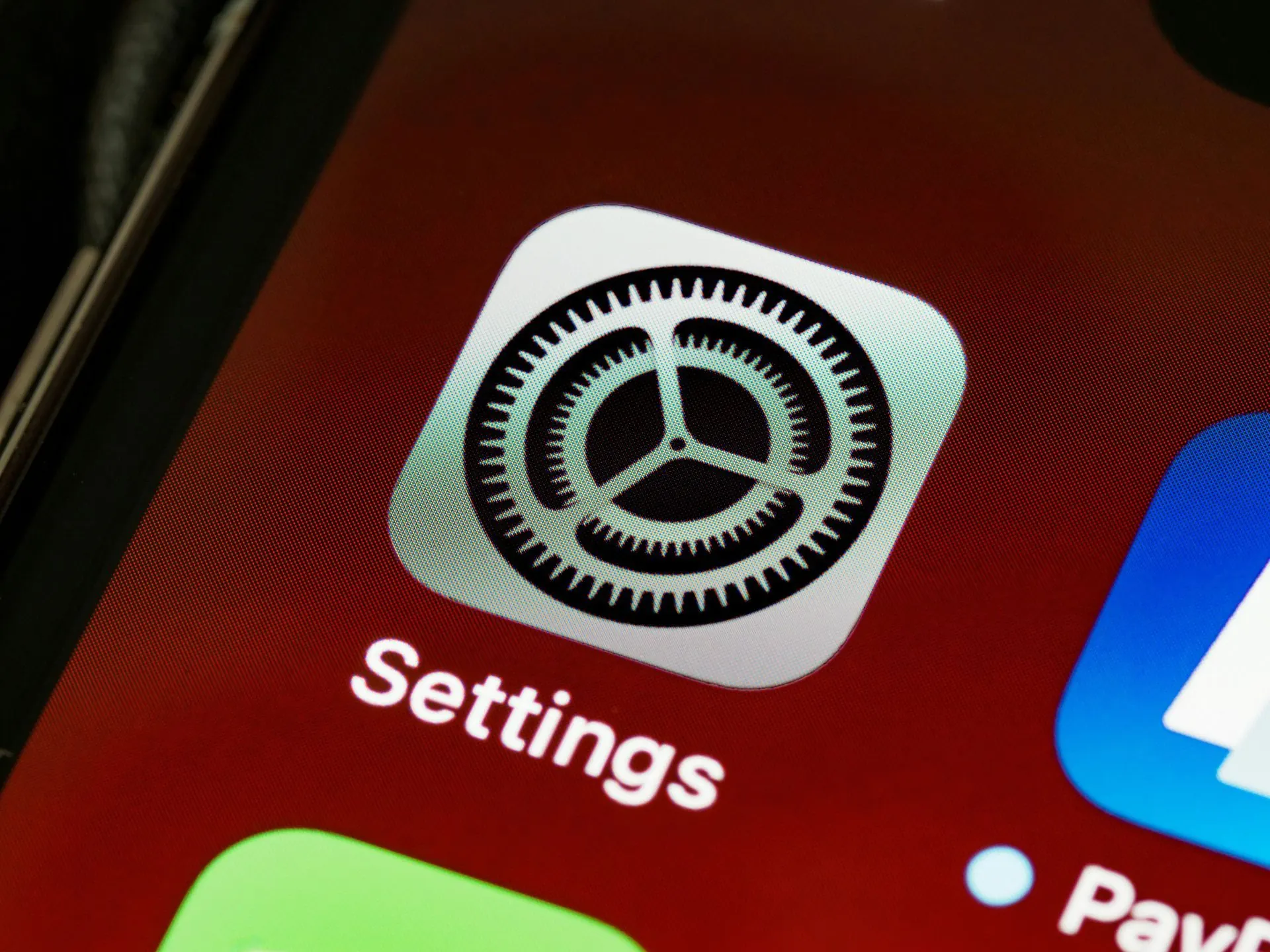 Das Symbol der Einstellungen-App auf einem Smartphone-Bildschirm zeigt ein weißes Zahnrad in einem Quadrat auf rotem Hintergrund.